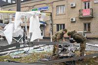 Police and security personnel inspect the remains of a shell in a street in Kyiv on February 24, 2022. - Russian President Vladimir Putin announced a military operation in Ukraine on Thursday with explosions heard soon after across the country and its foreign minister warning a 