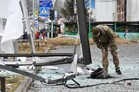 Police and security personnel inspect the remains of a shell in a street in Kyiv on February 24, 2022. - Russian President Vladimir Putin announced a military operation in Ukraine on Thursday with explosions heard soon after across the country and its foreign minister warning a 